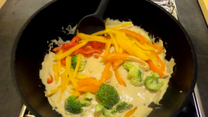 Adding vegetables to spicy coconut fish curry